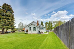 Einbungalow mit Schornstein, umzäunter Garten und einem großen Baum.