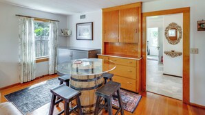 A kitchen with wooden cabinets, a glass-top table, and bar stools.