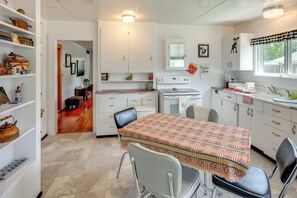 A kitchen with a dining table, chairs, cabinets, a refrigerator, and a window with a view.