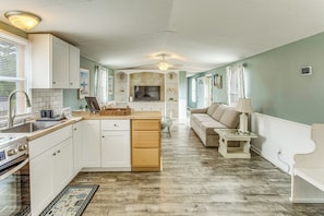 A compact kitchen with white cabinetry, a built-in oven, and a dining area with a table and chairs.