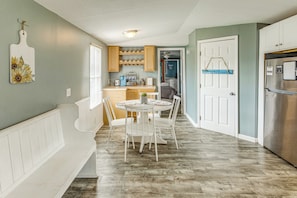 A kitchen with a dining area, wooden cabinets, a refrigerator, and a bench.