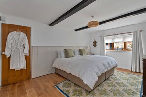 A bedroom with a bed, wooden door, and a window with curtains. - Poundtree (Wherwell)
