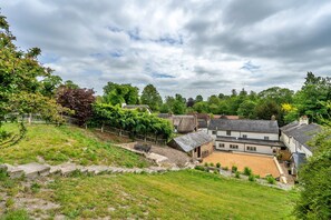 A rural setting with a thatched-roof house, a grassy area, and a stone wall. - Poundtree (Wherwell)