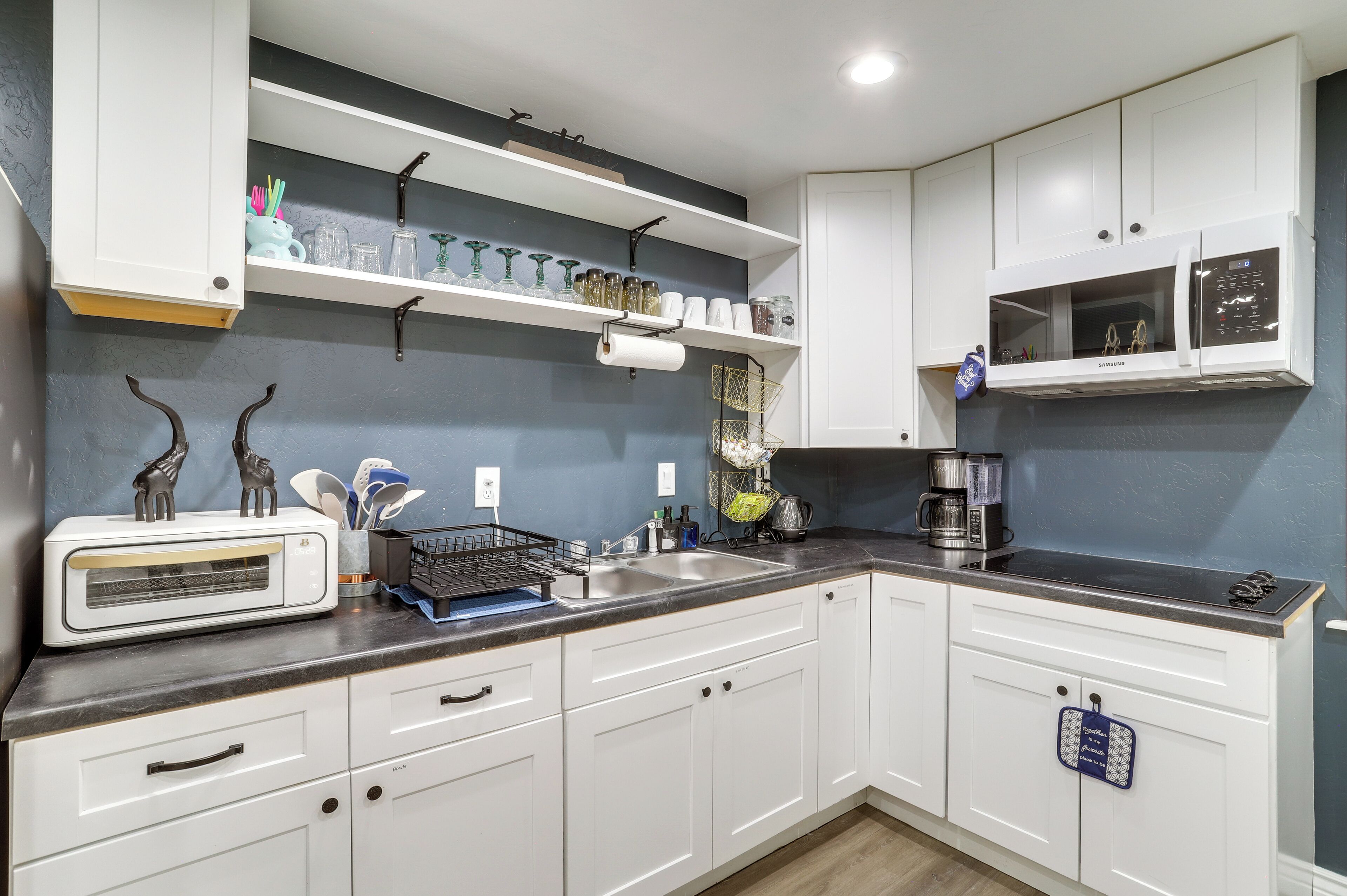 A kitchen with white cabinets, a microwave, a toaster, and various kitchen utensils.