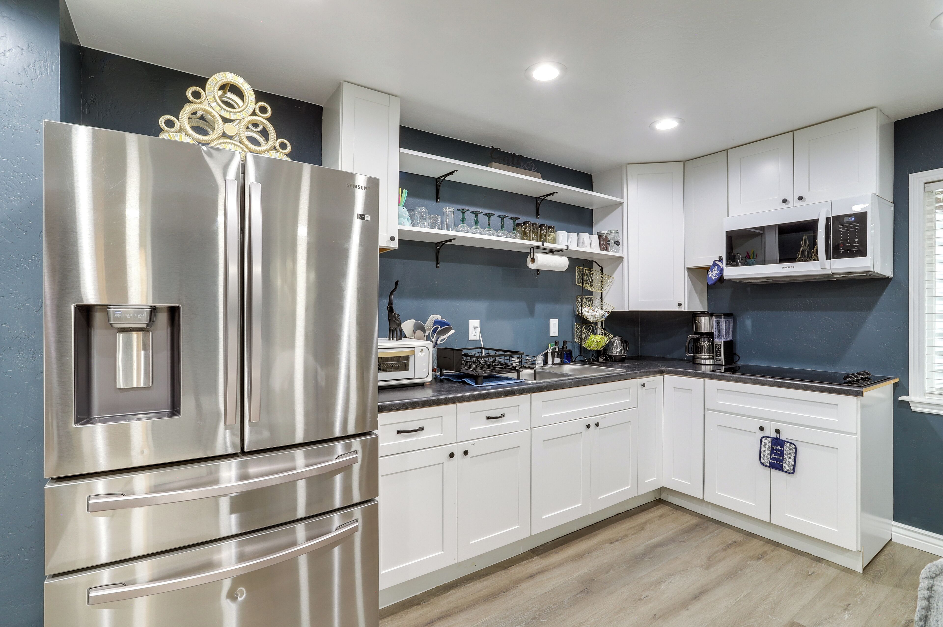 A modern kitchen with a stainless steel refrigerator, white cabinets, and a microwave.
