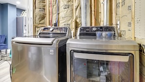 Twee wasmachines in een ruimte met blootliggende isolatie en houten balken.