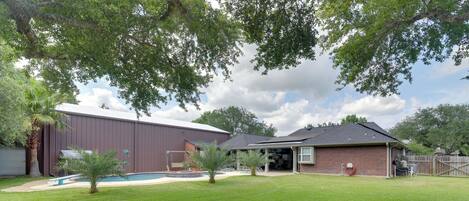 Une propriété résidentielle dotée d’une piscine, d’un grand garage et d’une maison en briques.