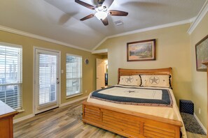 Un dormitorio con cama de madera, ventilador de techo y un cuadro en la pared.
