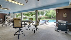An outdoor patio with a pool, grilling area, and seating. - Pool & Covered Patio! Galveston County Getaway (Dickinson)