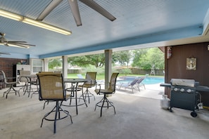 Un patio exterior con piscina, zona de barbacoa y mobiliario.