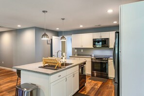 A modern kitchen with white cabinets, a stainless steel refrigerator, and a built-in oven.
