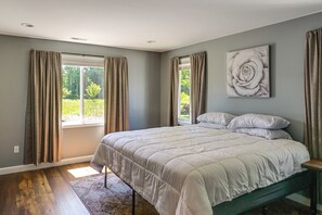 Une chambre à coucher avec un lit, des rideaux, une fenêtre et une œuvre d’art accrochée au mur.