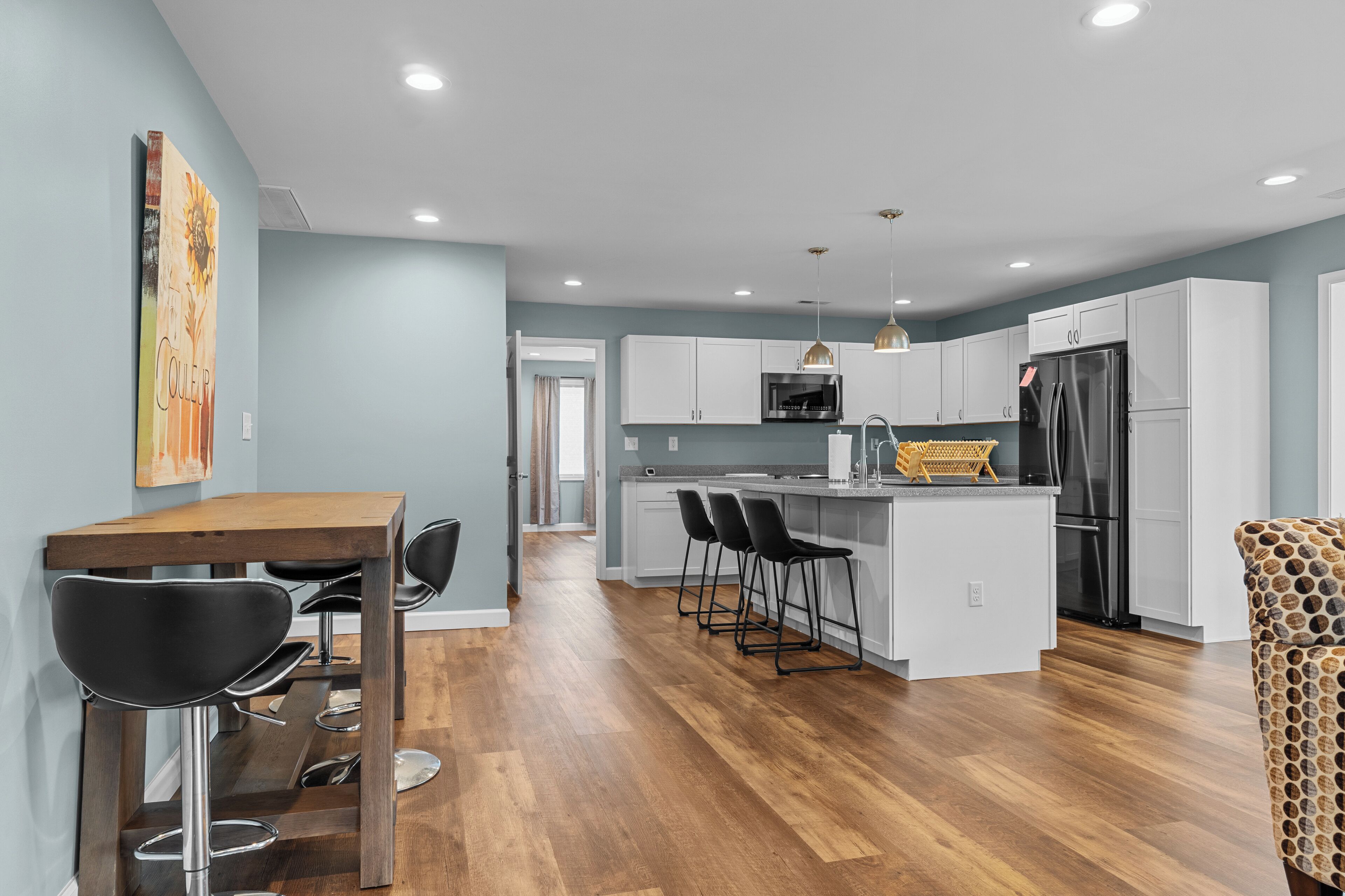 Cocina moderna con una isla central, taburetes de bar y una mesa de comedor con sillas.