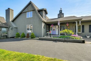 A two-story building with a grey exterior, a visible chimney, and a front porch with a purple door.