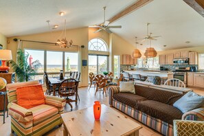 A spacious living area with a sofa, chairs, a dining table, and a kitchen with cabinets and appliances.