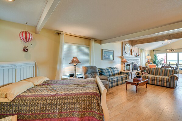 A spacious living area with a large bed, two sofas, a coffee table, and a fireplace. - Beachfront Lake Huron Home! Hike, Tube & Unwind (East Tawas)