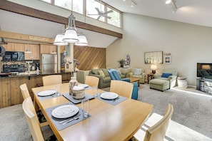 A modern kitchen with wooden cabinets, a stainless steel refrigerator, and a dining area with a wooden table set for four.