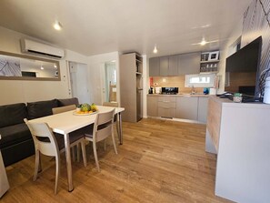 A modern kitchen with a dining area, a built-in oven, and a refrigerator. - Mobile home LAMA 1076 - Luxury & peace at Soline Camping Park (Biograd na Moru)