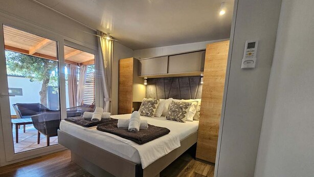 Quarto moderno com cama, mesinha e cadeira.