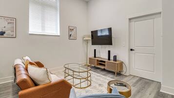 A living room with a sofa, coffee table, TV, and a door.