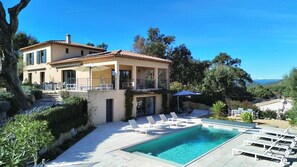 Una casa de dos pisos con piscina, mobiliario exterior y vistas al paisaje.