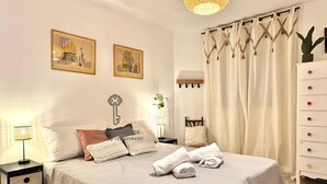 A neatly arranged bedroom with a bed, bedside tables, a dresser, and two wall-mounted paintings. - Spacious 5-bedroom house with AC and Pool (Le Plan-de-la-Tour)