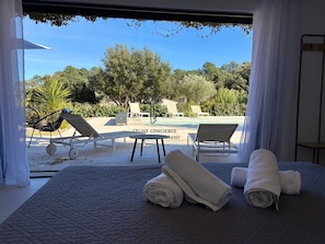 Une chambre avec vue sur une piscine et un espace salon extérieur.