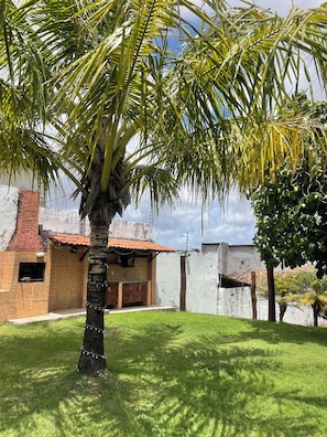 A brick building with a tiled roof, a palm tree, and a grassy lawn.