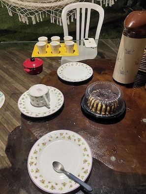 A dining table with plates, cups, a teapot, a cake, and a smartphone.