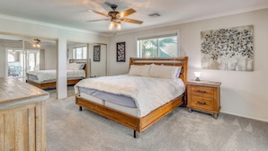 A bedroom with a wooden bed, a nightstand, a ceiling fan, and a large window. - 2 Mi to Windsor Boat Launch! Lake-view Escape (Lake Havasu City)