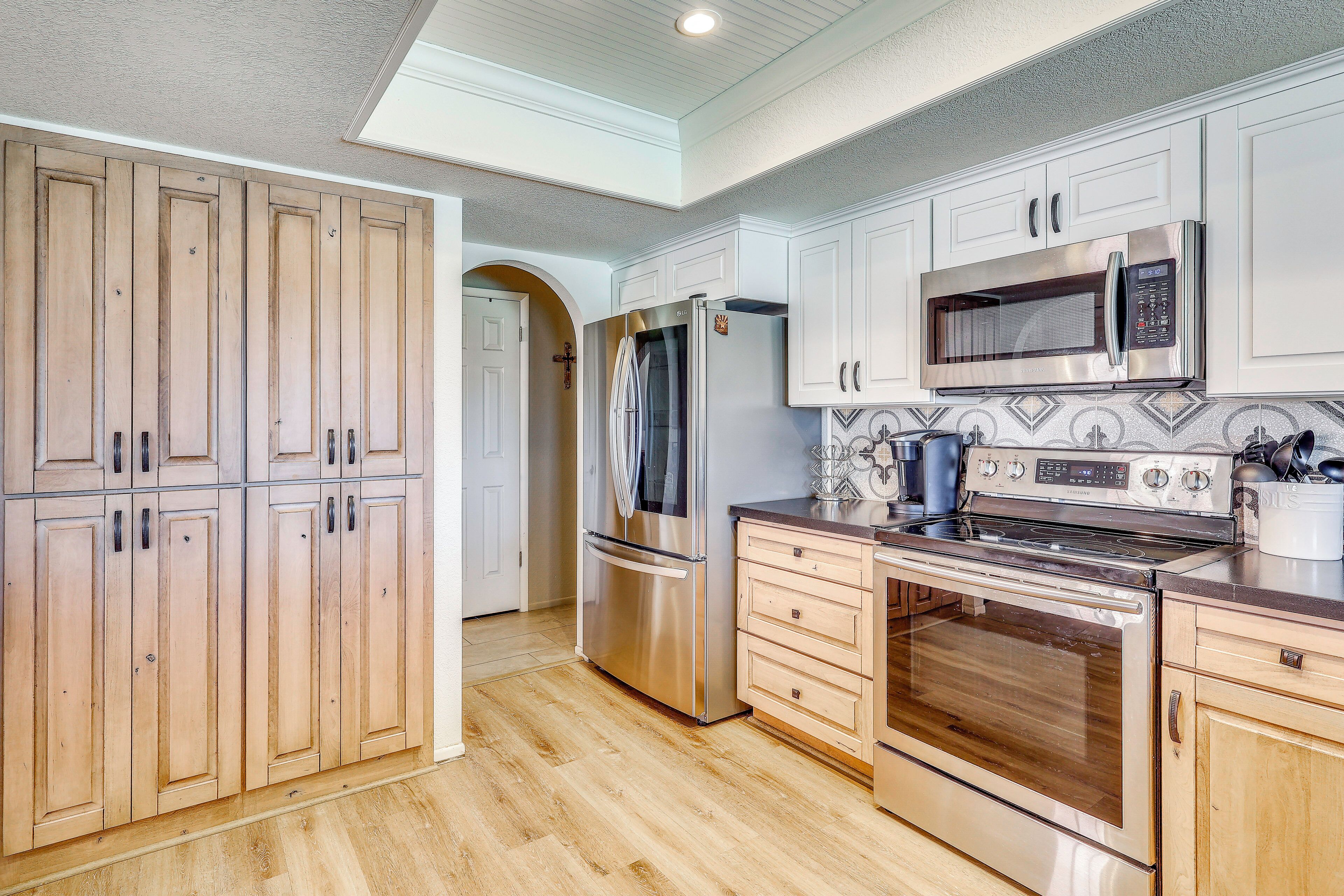 A kitchen with wooden cabinets, stainless steel appliances, and a tiled backsplash.