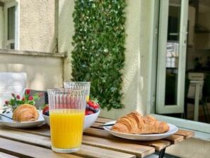 Een ontbijttafel met croissants, een glas sinaasappelsap en een schaal bessen.