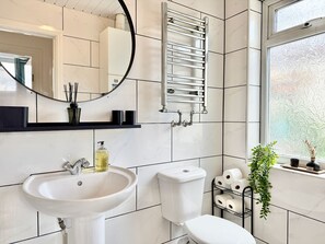 Een moderne badkamer met een wit wastafelmeubel, toilet en handdoekhouder.