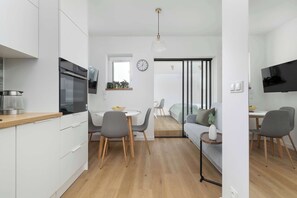 Eine moderne Küche mit weißen Schränken, einem eingebauten Ofen und einem Essbereich mit rundem Tisch und Stühlen.
