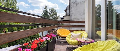A balcony with wooden railings, potted plants, and yellow bean bag chairs.