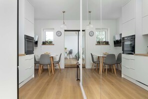 Eine moderne Küche mit weißen Schränken, Holzböden und Pendelleuchten.