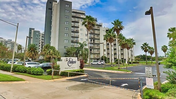 A hotel entrance with a sign, palm trees, and a multi-story building in the background. - 2 Miles to Universal - Lake View -Sleeps 6 (Orlando)