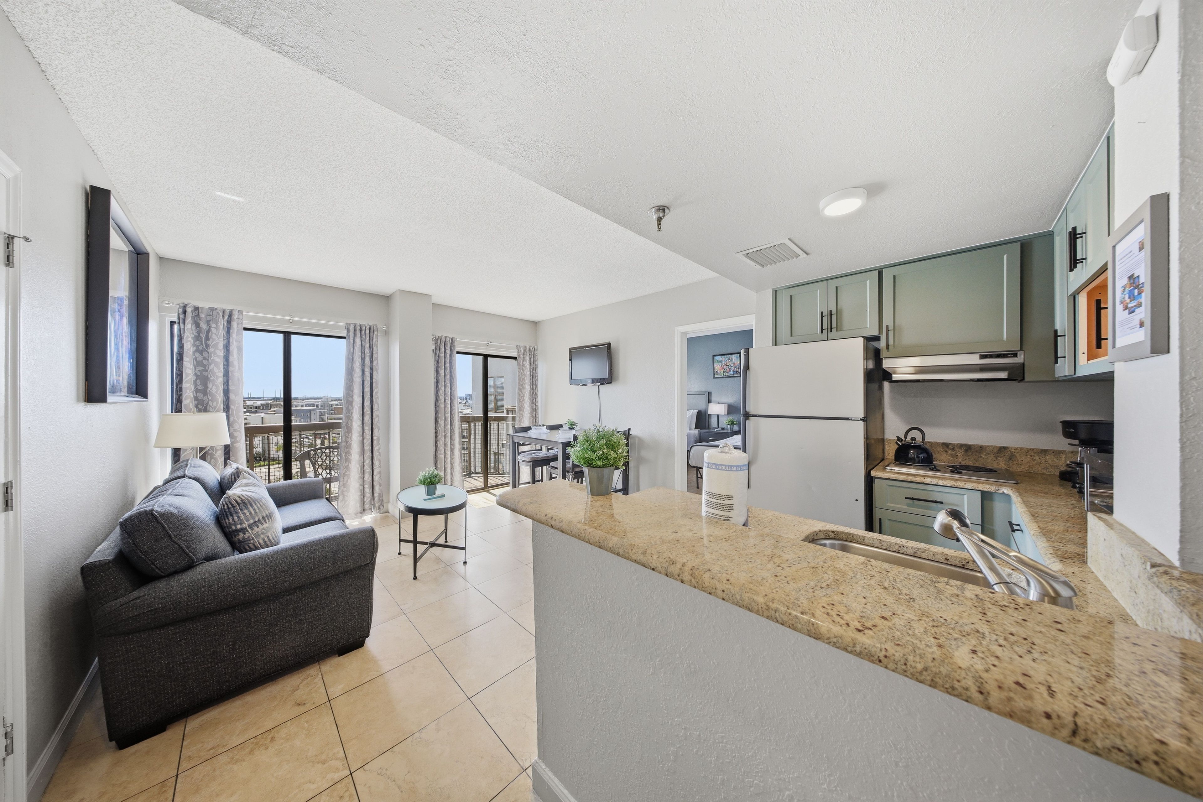 A modern apartment with a living area, kitchenette, and a balcony with a city view.