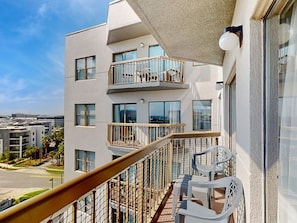 Ein modernes Apartmenthaus mit Balkon, Blick auf die Stadt und blauem Himmel.