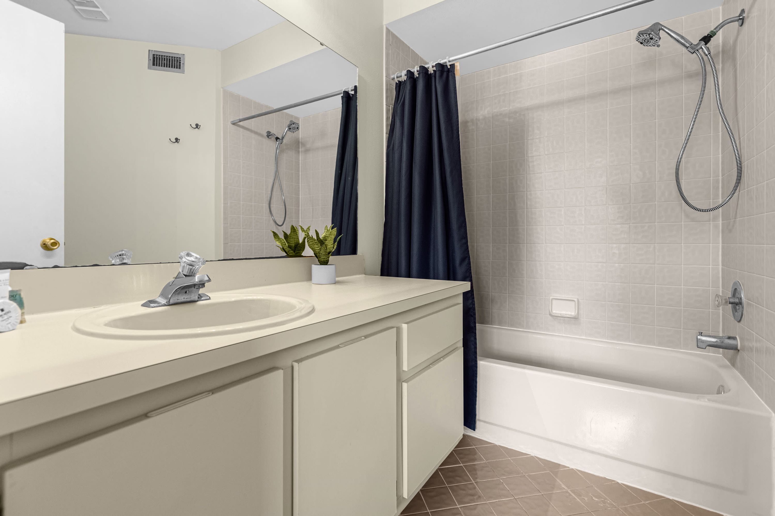 A modern bathroom with a bathtub, shower, and a sink with a mirror.