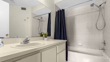 A modern bathroom with a bathtub, shower, and a sink with a mirror.