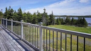 Una terraza de madera con barandilla que da a un lago y un bosque.