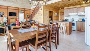 Un interior de madera con comedor, cocina y una escalera que sube a un nivel superior.