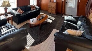 Una sala de estar con techo de madera, televisión, sofá, mesa de centro y chimenea.