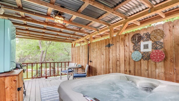 Eine Holzterrasse mit Whirlpool, einem Tisch mit Stühlen und dekorativen Tellern an der Wand.