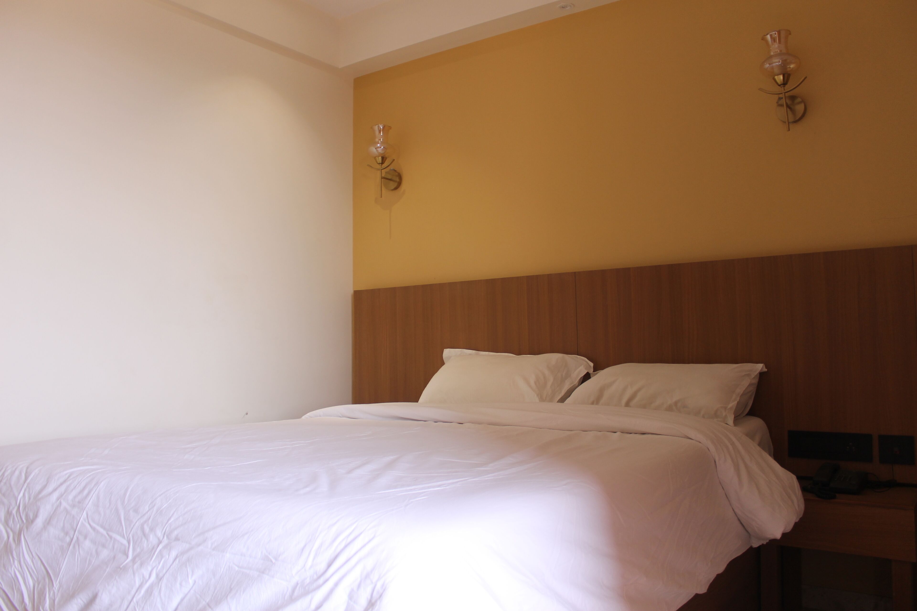 Un dormitorio con una cama grande, cabecero de madera y dos lámparas de pared.
