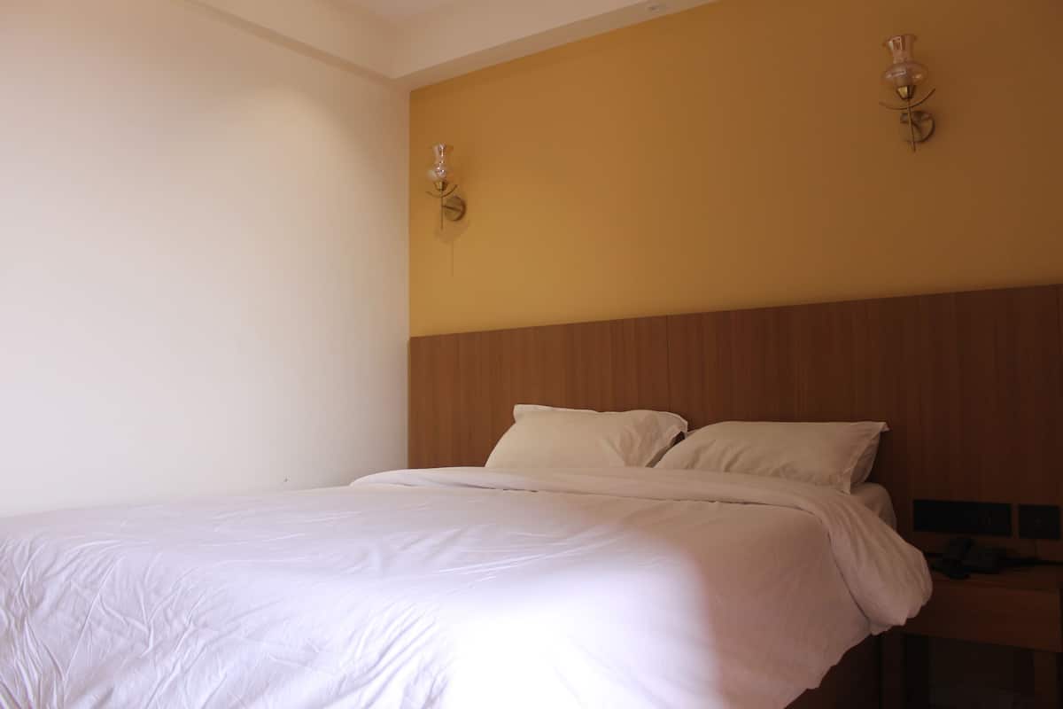 A bedroom with a large bed, wooden headboard, and two wall-mounted light fixtures.