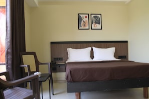A hotel room with a bed, a desk, a chair, and two wall-mounted artworks.
