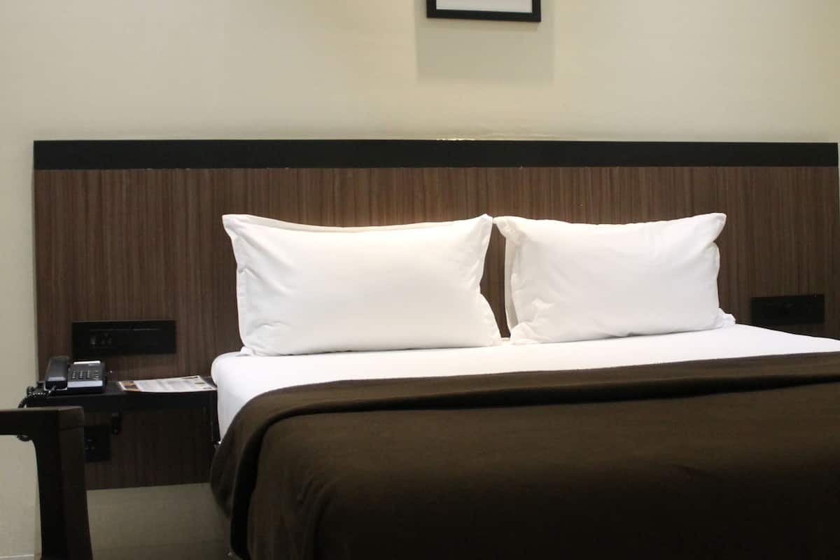 A hotel room with a bed, a nightstand, a lamp, and a framed picture on the wall.
