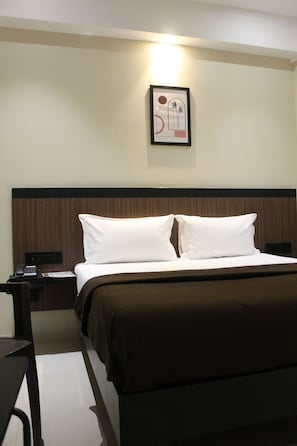 Una habitación de hotel con una cama, una mesita de noche, una lámpara y un cuadro en la pared.